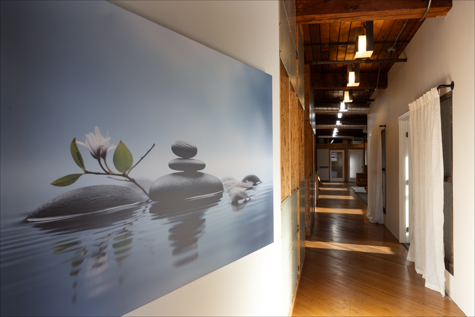 Individual Experience 3 Serene hallway at Experience Onward retreat center featuring a large wall mural of stacked stones and a flower, symbolizing tranquility and healing.