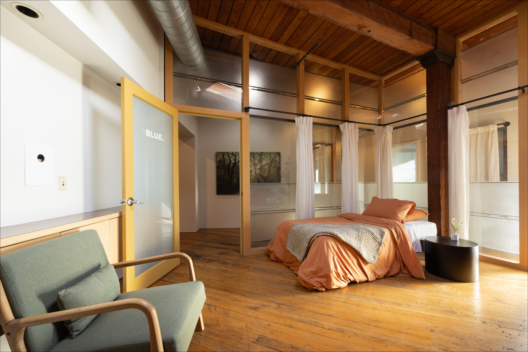 Individual Experience 8 Cozy retreat room featuring warm orange bedding, minimalist decor, and natural light, emphasizing a serene and inviting atmosphere for personal growth and healing.